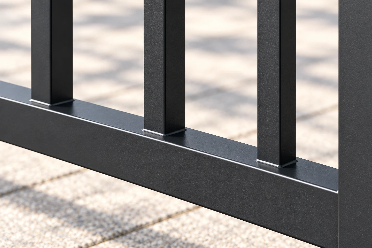 Close view of charcoal vertical pickets joined to the lower rail of an aluminium railing panel.
